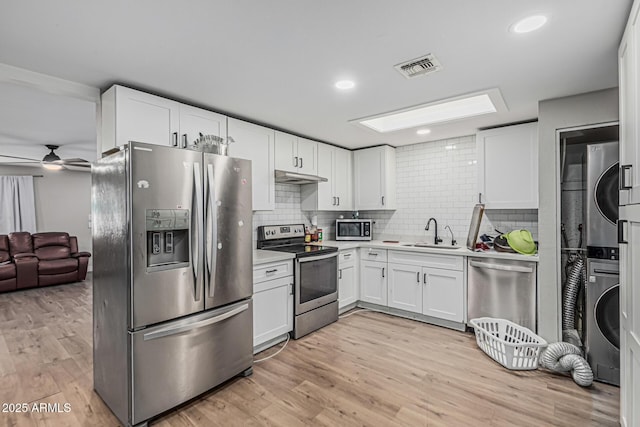 13039 N 19th Ave, Phoenix, AZ 85029 - kitchen with stainless steel appliances, stacked washer / dryer, a sink, white cabinetry, and light countertops