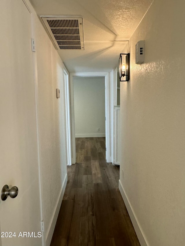 corridor featuring a textured ceiling and dark wood-type flooring