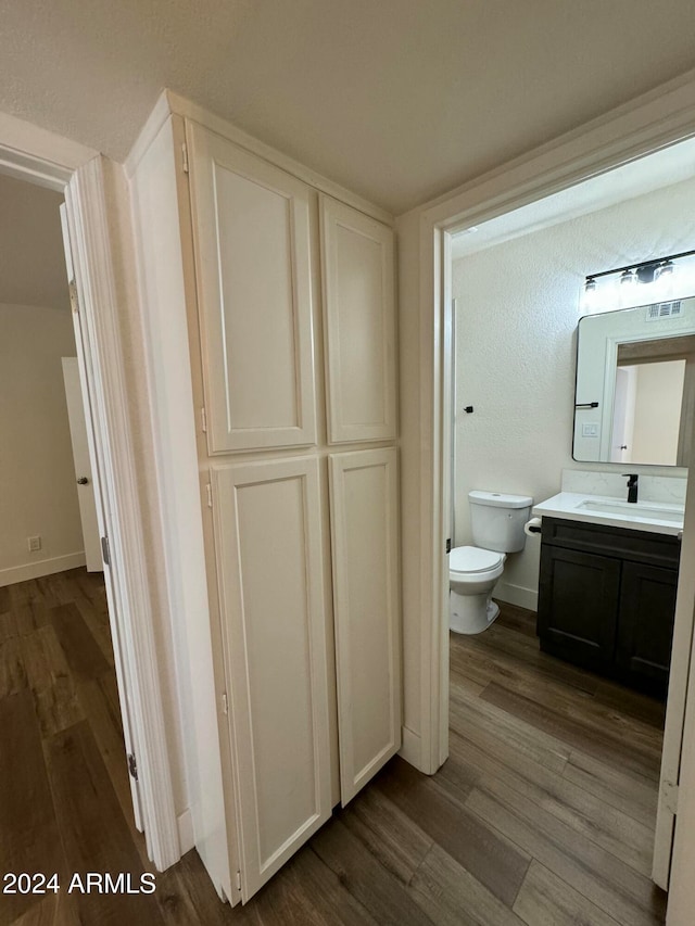 bathroom featuring vanity, wood-type flooring, and toilet