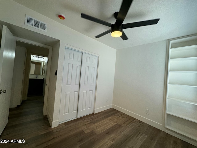 unfurnished bedroom featuring ceiling fan, a textured ceiling, a closet, and dark hardwood / wood-style flooring