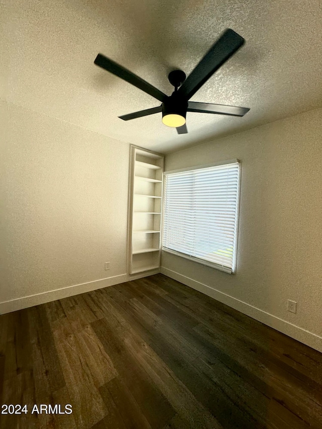 spare room featuring a textured ceiling, dark wood-type flooring, and ceiling fan