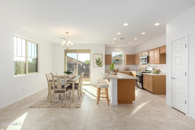 kitchen featuring pendant lighting, a center island with sink, appliances with stainless steel finishes, an inviting chandelier, and a breakfast bar area