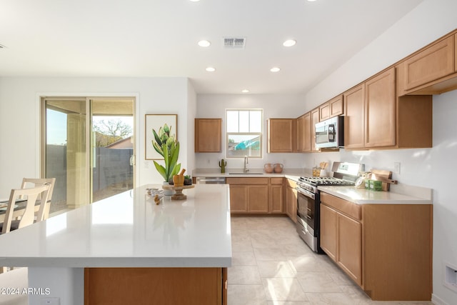 kitchen with a center island, light tile patterned floors, sink, and stainless steel appliances