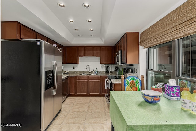 kitchen featuring appliances with stainless steel finishes, a raised ceiling, light tile floors, sink, and light stone countertops