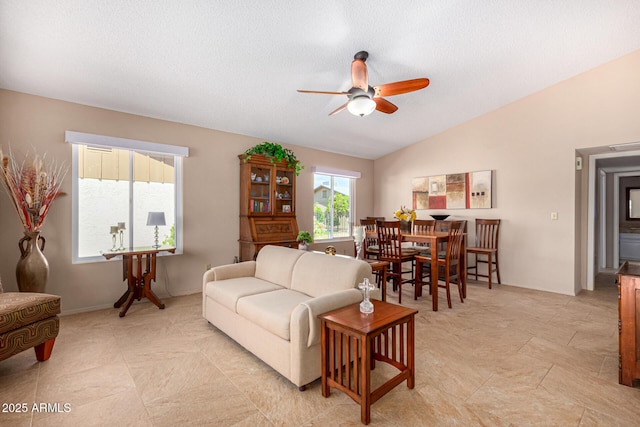 living room featuring ceiling fan, a textured ceiling, and lofted ceiling