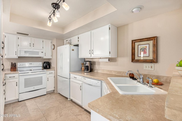 kitchen featuring visible vents, a sink, a tray ceiling, white appliances, and white cabinetry