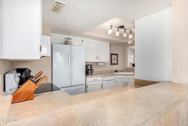 kitchen with visible vents, light countertops, track lighting, white cabinets, and white appliances