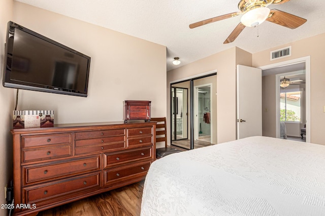 bedroom with dark wood-style flooring, a ceiling fan, visible vents, and a closet