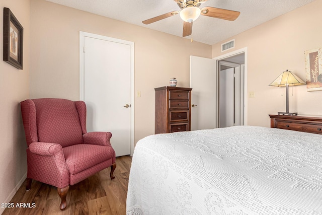 bedroom with baseboards, ceiling fan, visible vents, and wood finished floors