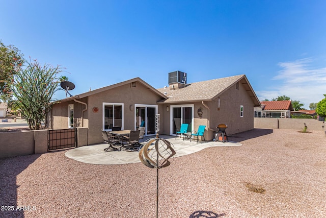 rear view of property with fence, stucco siding, a gate, central AC unit, and a patio area