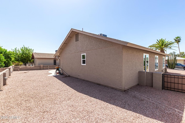 view of side of home featuring stucco siding and fence