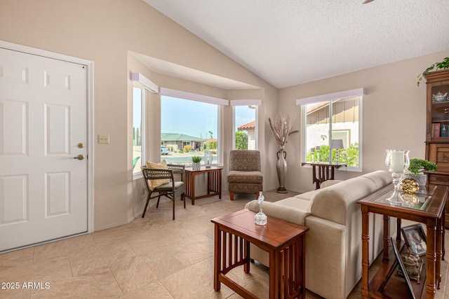 living area with baseboards, a textured ceiling, and vaulted ceiling