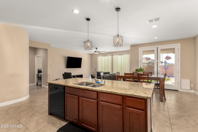 kitchen with hanging light fixtures, an island with sink, ceiling fan, sink, and black dishwasher