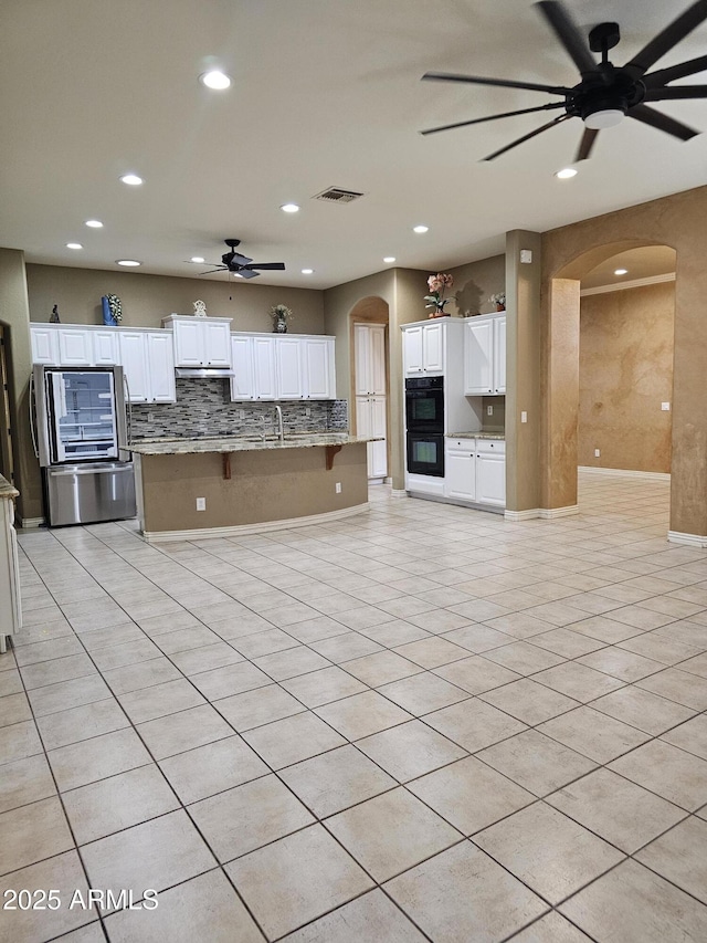 14380 W Monte Vista Rd, Goodyear, AZ 85395 - kitchen with ceiling fan, arched walkways, backsplash, recessed lighting, and white cabinets