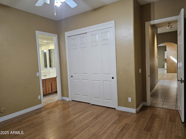14380 W Monte Vista Rd, Goodyear, AZ 85395 - unfurnished bedroom with arched walkways, light wood finished floors, a closet, a sink, and a textured wall