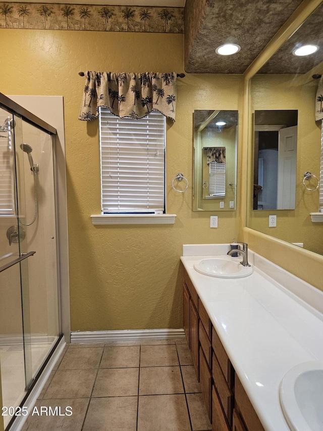 14380 W Monte Vista Rd, Goodyear, AZ 85395 - bathroom with double vanity, a stall shower, baseboards, tile patterned flooring, and a textured wall