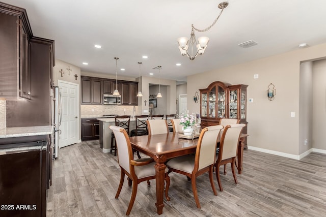 dining area with an inviting chandelier and light wood-type flooring