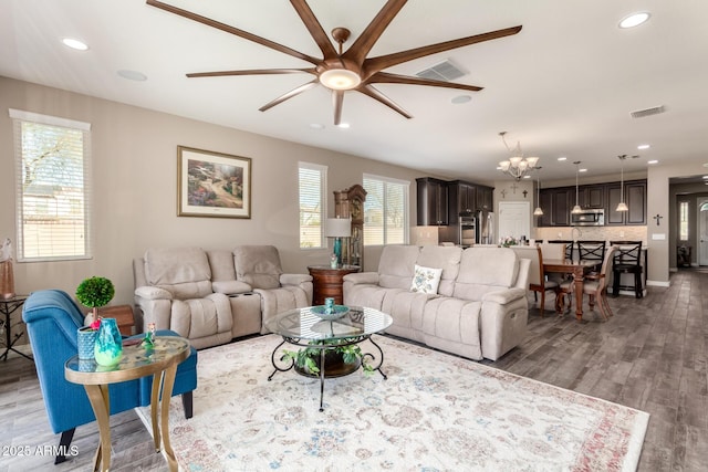 living room featuring hardwood / wood-style flooring and ceiling fan with notable chandelier