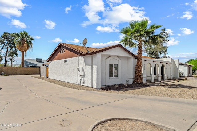 view of home's exterior with stucco siding and fence