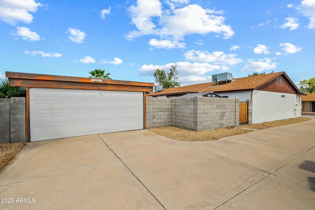 garage with concrete driveway and fence