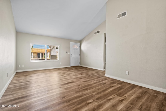 unfurnished living room with wood finished floors, baseboards, vaulted ceiling, and visible vents