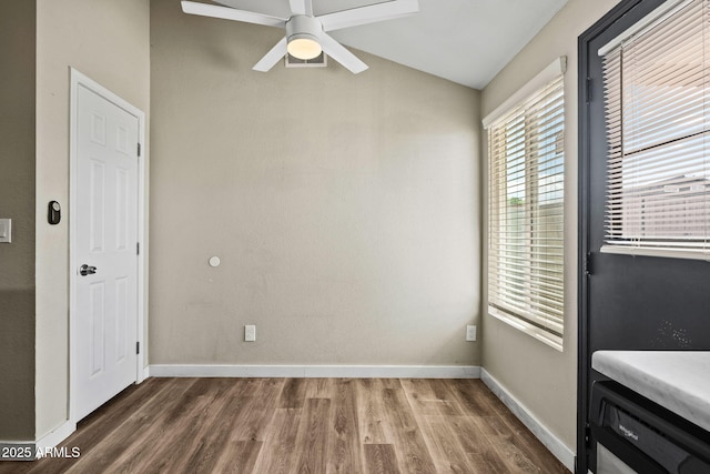 unfurnished dining area featuring ceiling fan, vaulted ceiling, wood finished floors, and baseboards