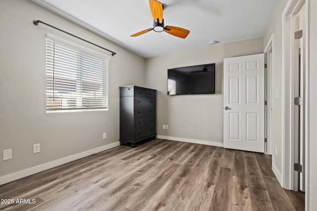 unfurnished bedroom featuring wood finished floors, baseboards, and a ceiling fan