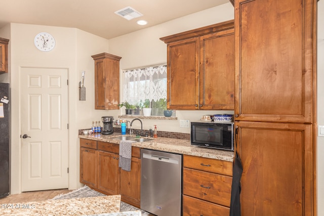 kitchen with appliances with stainless steel finishes, light stone countertops, and sink