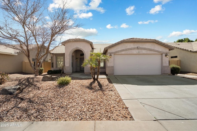 mediterranean / spanish house with a garage, driveway, a tile roof, and stucco siding