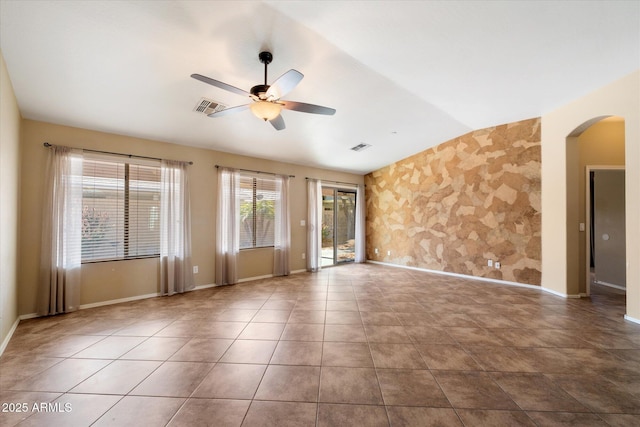 tiled empty room with a ceiling fan, visible vents, vaulted ceiling, and arched walkways