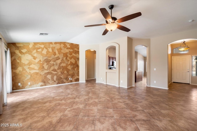 spare room with baseboards, visible vents, arched walkways, a ceiling fan, and lofted ceiling