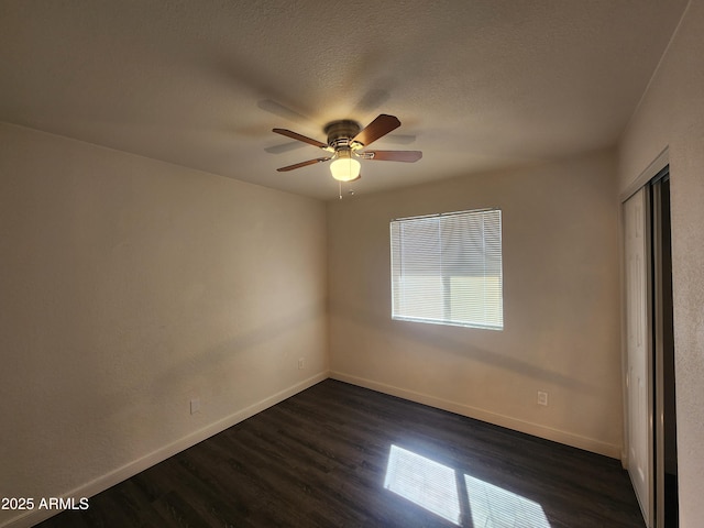 spare room featuring a textured ceiling, dark wood-style flooring, a ceiling fan, and baseboards