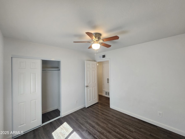 unfurnished bedroom featuring baseboards, visible vents, a ceiling fan, dark wood finished floors, and a closet