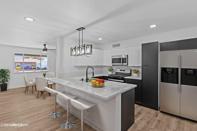 kitchen featuring a sink, stainless steel appliances, a breakfast bar, visible vents, and a peninsula