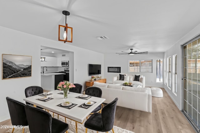 dining space with baseboards, visible vents, a ceiling fan, and light wood-style floors
