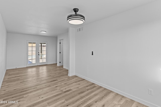 empty room featuring baseboards, visible vents, light wood-style floors, and french doors