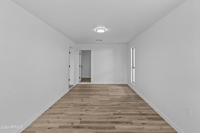 hall with visible vents, light wood finished floors, and baseboards