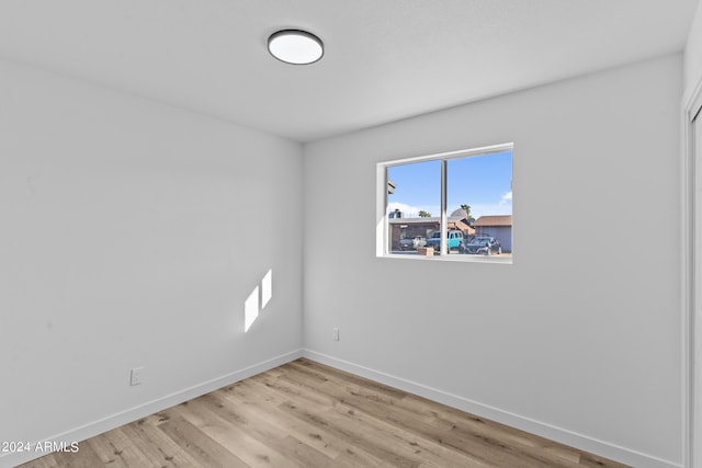 spare room featuring baseboards and light wood-style flooring