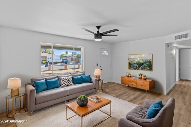 living room featuring baseboards, visible vents, a ceiling fan, and light wood finished floors