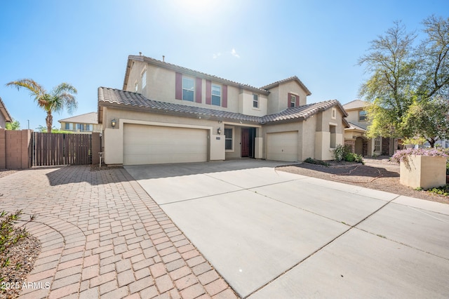 view of front of house with a tile roof, driveway, fence, and stucco siding