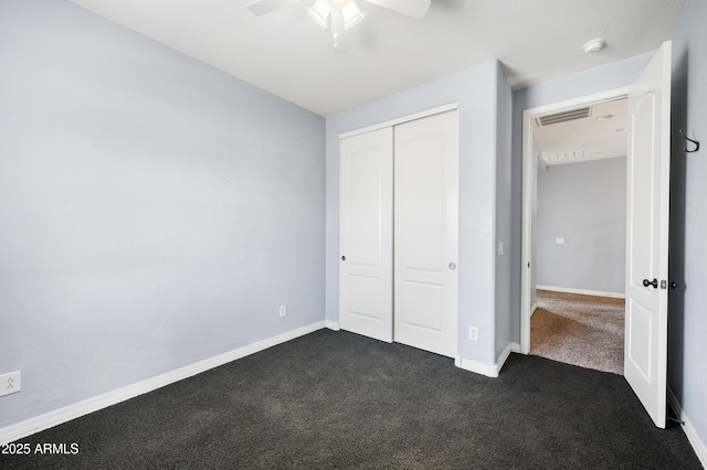 unfurnished bedroom with a closet, visible vents, dark carpet, and baseboards