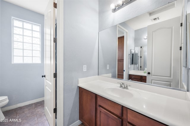 bathroom featuring visible vents, toilet, vanity, tile patterned flooring, and baseboards