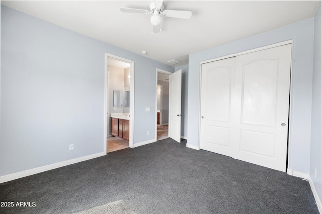 unfurnished bedroom featuring dark colored carpet, a closet, ensuite bathroom, ceiling fan, and baseboards