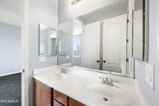 bathroom featuring double vanity, a sink, and baseboards