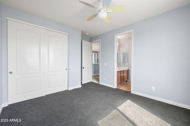 unfurnished bedroom featuring a closet, dark carpet, a ceiling fan, connected bathroom, and baseboards