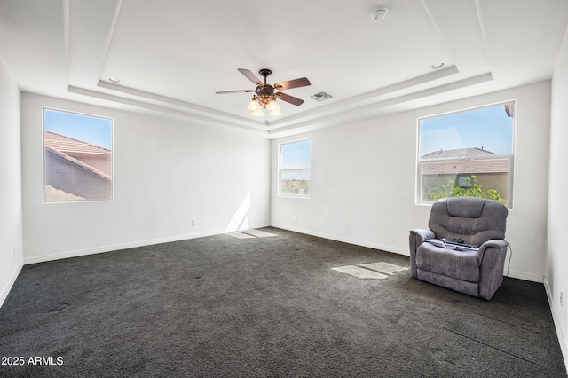 unfurnished room featuring a tray ceiling, baseboards, visible vents, and dark colored carpet