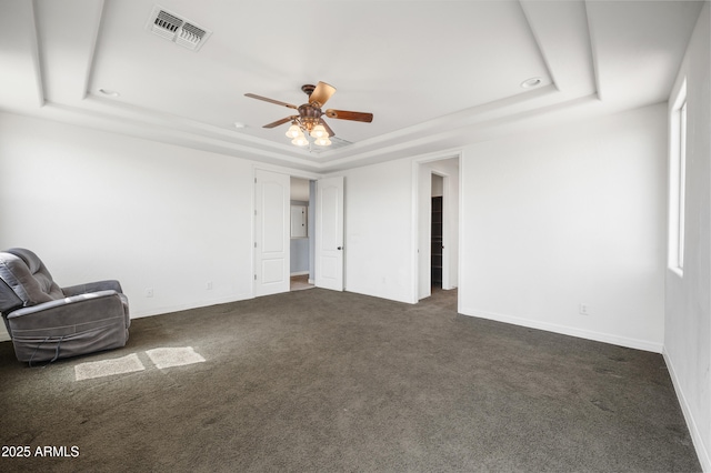 interior space with visible vents, a raised ceiling, a ceiling fan, and dark colored carpet