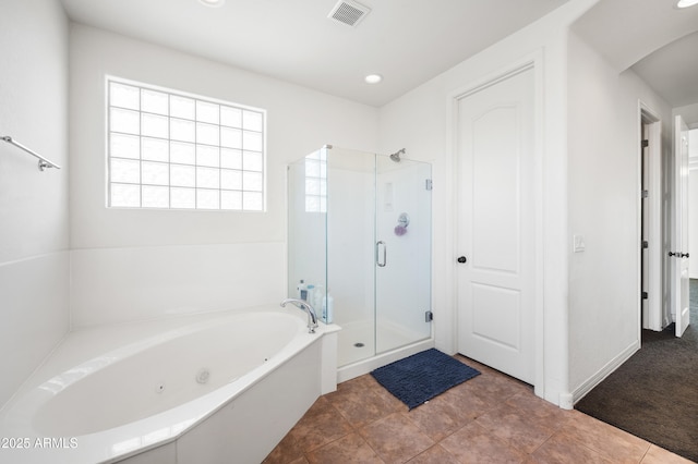 bathroom featuring a wealth of natural light, visible vents, a jetted tub, and a shower stall