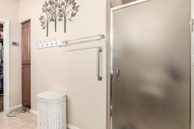 bathroom with a shower stall, a spacious closet, baseboards, and tile patterned floors