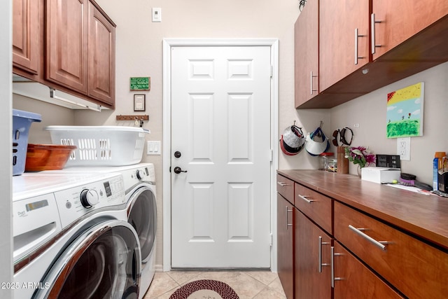 clothes washing area featuring light tile patterned flooring, washing machine and dryer, and cabinet space